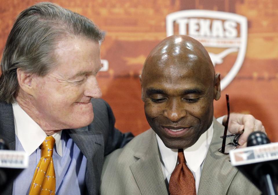 FILE - In this Monday, Jan. 6, 2014 file photo, Charlie Strong, right, is hugged by University of Texas at Austin President Bill Powers, left, during an NCAA college football news conference in Austin, Texas where Strong was introduced as the university's new football coach. Richard Lapchick, who has spent decades advocating for more diversity in sports, says, "There's no question that the so-called prime jobs, programs with great traditions, have been less available to African-Americans." He said it has been tougher for black coaches to build winning traditions because they usually get opportunities with losing teams, and it’s tough to turn that around before the ax falls in two or three years. "Stepping in at Texas or Penn State," Lapchick said, "makes that a lot easier." (AP Photo/Eric Gay)