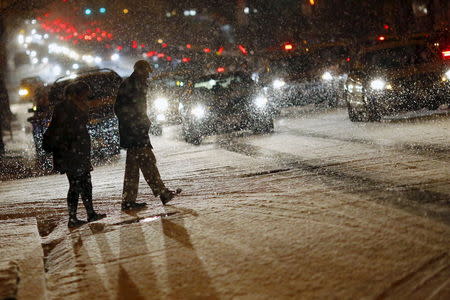 People cross a street as it snows in Washington, January 20, 2016. REUTERS/Carlos Barria