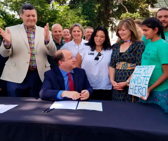 <p>Madhvi4EcoEthics</p> Madhvi (in 2021) watches Colorado governor Jared Polis sign the state’s plastic and styrofoam ban bill into law.