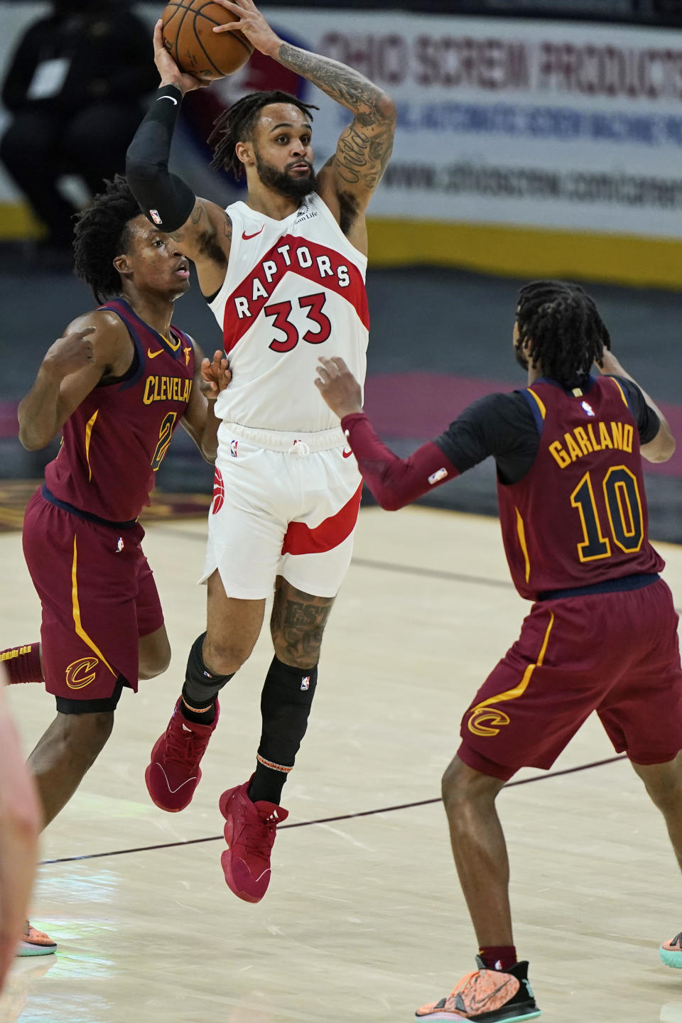 Toronto Raptors' Gary Trent Jr. (33) looks to pass against Cleveland Cavaliers' Collin Sexton (2) and Darius Garland (10) in the second half of an NBA basketball game, Saturday, April 10, 2021, in Cleveland. (AP Photo/Tony Dejak)