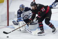 Ottawa Senators right wing Connor Brown (28) tries to put the puck past Winnipeg Jets goaltender Connor Hellebuyck during second-period NHL hockey game action Monday, April 12, 2021, in Ottawa, Ontario. (Adrian Wyld/The Canadian Press via AP)