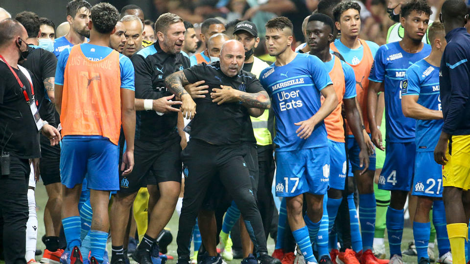 Seen here, Marseille coach Jorge Sampaoli is restrained by officials after reacting angrily to the incident.