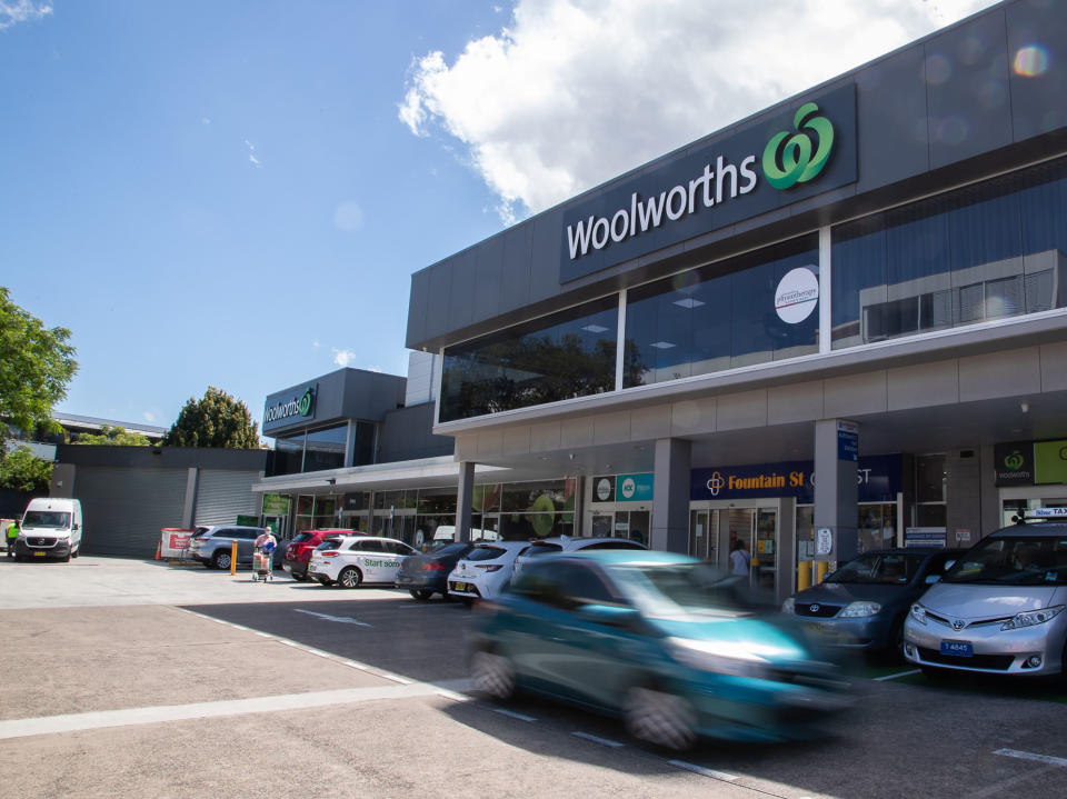 A Woolworths store from exterior showing car going past.