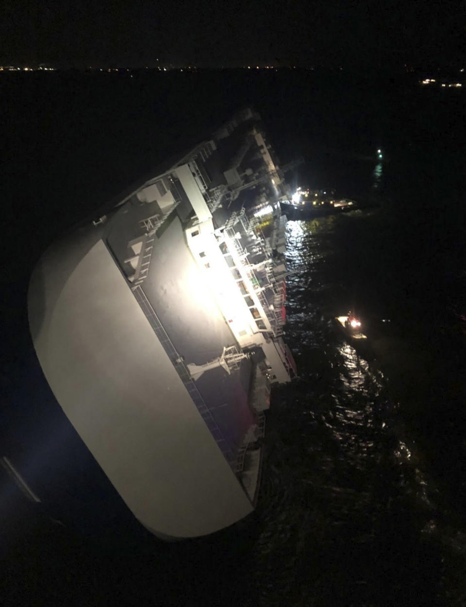 In this photo provided by the U.S. Coast Guard, the Golden Ray cargo ship lists to one side near a port on the Georgia coast, early Sunday, Sept. 8, 2019. The ship, carrying vehicles, was being evacuated after sharply listing. The U.S. Coast Guard said the vessel was leaving Brunswick when it somehow turned drastically sideways early Sunday. (U.S. Coast Guard via AP)