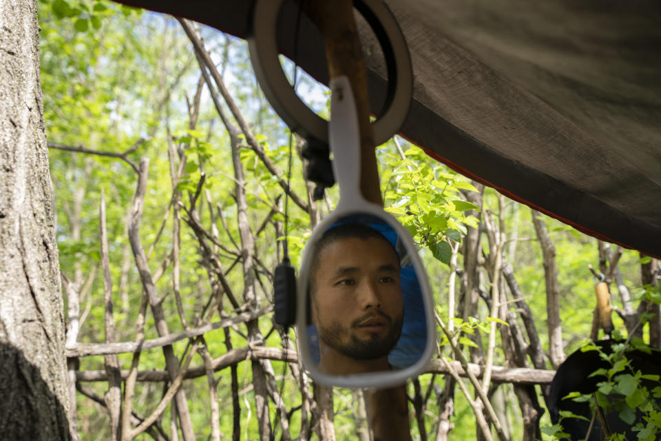 Chen Wang, a Chinese migrant currently homeless in New York, is reflected in a mirror at his camp site, Friday, May 3, 2024. Chen came to the U.S. after getting criminally admonished by Chinese police for anti-Chinese Communist Party posts on X, formerly known as Twitter. The daily struggle to find work for Chinese immigrants living illegally in New York is a far cry from the picture Donald Trump and other Republicans have sought to paint about them. Asian advocacy organizations say they're concerned the exaggerated rhetoric could fuel further harassment against Asians in the U.S. (AP Photo/Serkan Gurbuz)