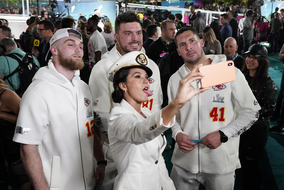 Gerdina Holguin, with TUDN television, poses with Kansas City Chiefs players during Opening Night for the NFL Super Bowl 54 football game Monday, Jan. 27, 2020, at Marlins Park in Miami. (AP Photo/David J. Phillip)