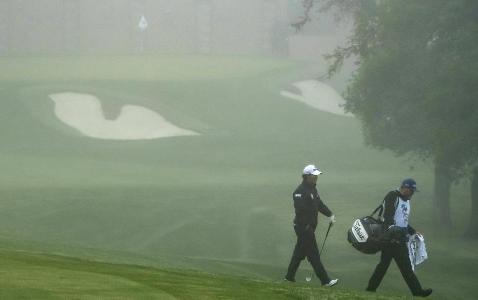 Golfer S.H. Kim, South Korea, and caddie, Micah Fugitt, walks off of the No. 10 fairway after play was suspended due to heavy fog during the first round of the Valero Texas Open golf tournament, Thursday, March 30, 2023, in San Antonio. (AP Photo/Rodolfo Gonzalez )