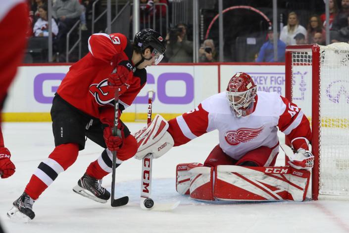 Detroit Red Wings goaltender Jonathan Bernier makes a save on New Jersey Devils center Nico Hischier during the second period at Prudential Center, Nov. 23, 2019 in Newark, N.J.