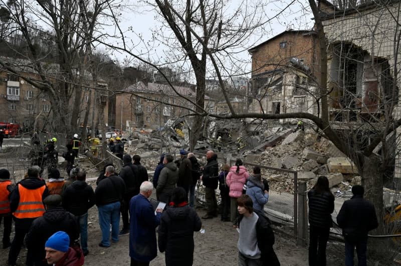 People look on as rescuers search a destroyed building following a missile attack by the Russian army on Kiev. Sergei Chuzavkov/Zuma Press/dpa