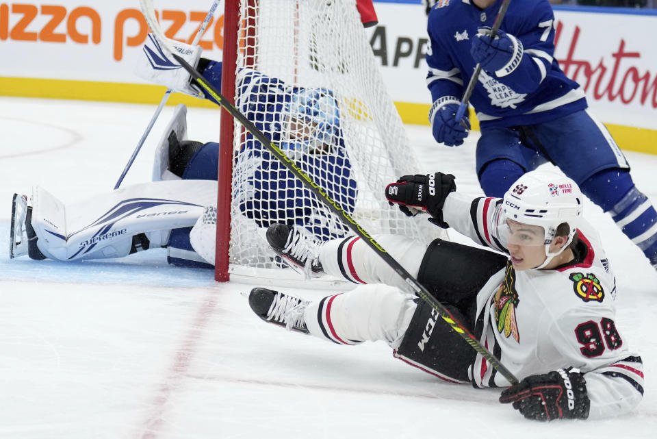 Chicago Blackhawks center Connor Bedard (98) crashes into Toronto Maple Leafs goaltender Joseph Woll (60) during third-period NHL hockey game action in Toronto, Monday, Oct. 16, 2023. (Nathan Denette/The Canadian Press via AP)