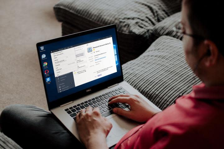 A person using the 1Password password manager on a laptop while sat on a couch.