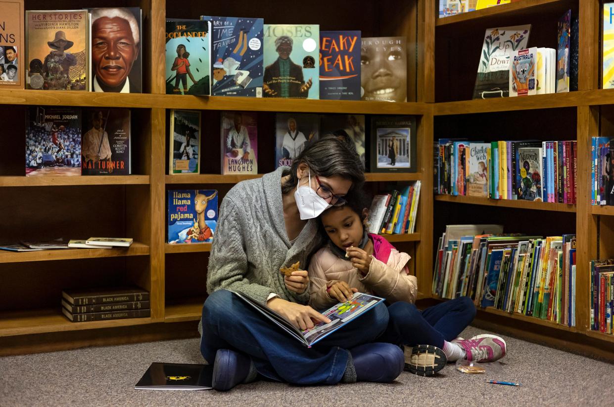 Bonnie Osei-Frimpong reads to her daughter, Graham, 7, in the Joy Village School’s library during a preview day for potential students and their families on Saturday, Feb. 5, 2022 in Athens.