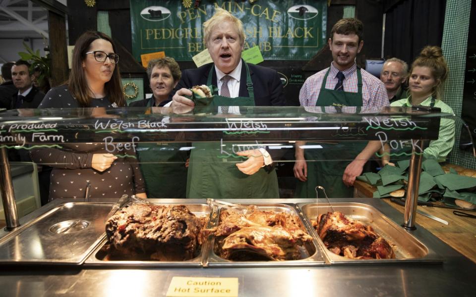 Britain's Prime Minister Boris Johnson greets customers on a stall selling meat sandwiches - Dan Kitwood/Getty Images