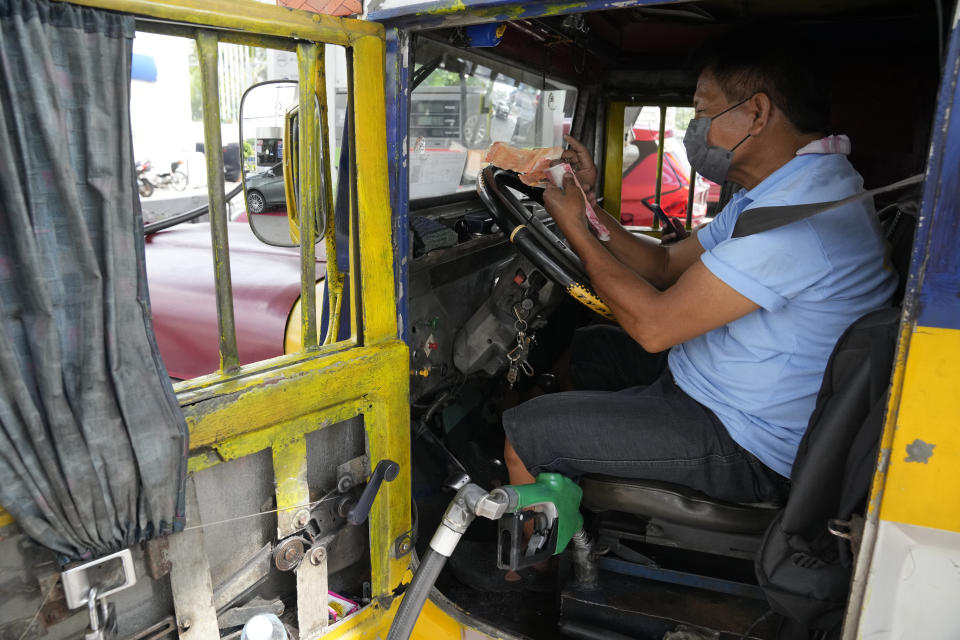 A passenger jeepney driver counts money from his earnings which he will use to refuel his vehicle at a gasoline station in Quezon City, Philippines on Monday, June 20, 2022. Around the world, drivers are looking at numbers on the gas pump and rethinking their habits and finances. (AP Photo/Aaron Favila)