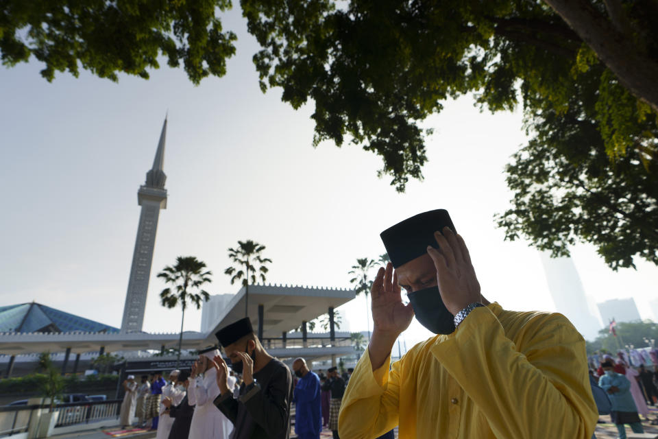 Muslims wearing protective masks pray outside the National Mosque while celebrating Eid al-Fitr, the Muslim festival marking the end the holy fasting month of Ramadan in Kuala Lumpur, Malaysia, Thursday, May 13, 2021. (AP Photo/Vincent Thian)