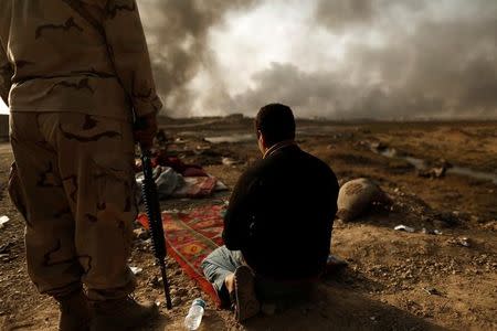 An Iraqi soldier stands next to a detained man accused of being an Islamic State fighter at a check point in Qayyara, south of Mosul, Iraq October 30, 2016. REUTERS/Zohra Bensemra