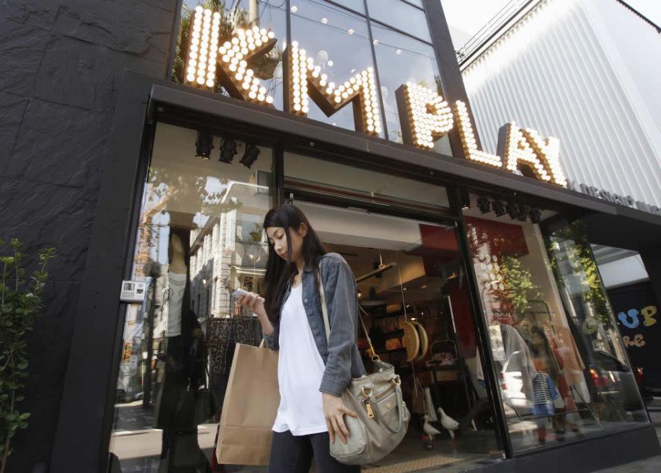 A woman looks at her smartphone as she walks past a store on the Garosugil or the Tree-Lined Street in the Gangnam area of Seoul.