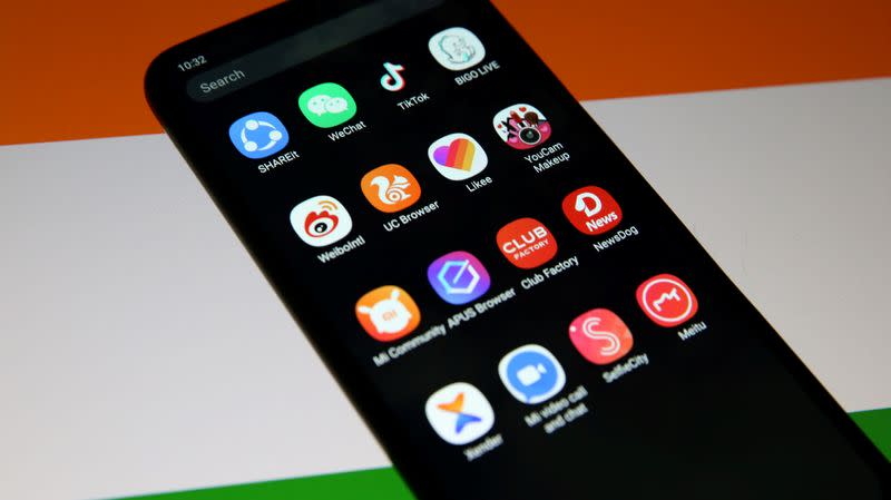 Smartphone with Chinese applications is seen in front of a displayed Indian flag