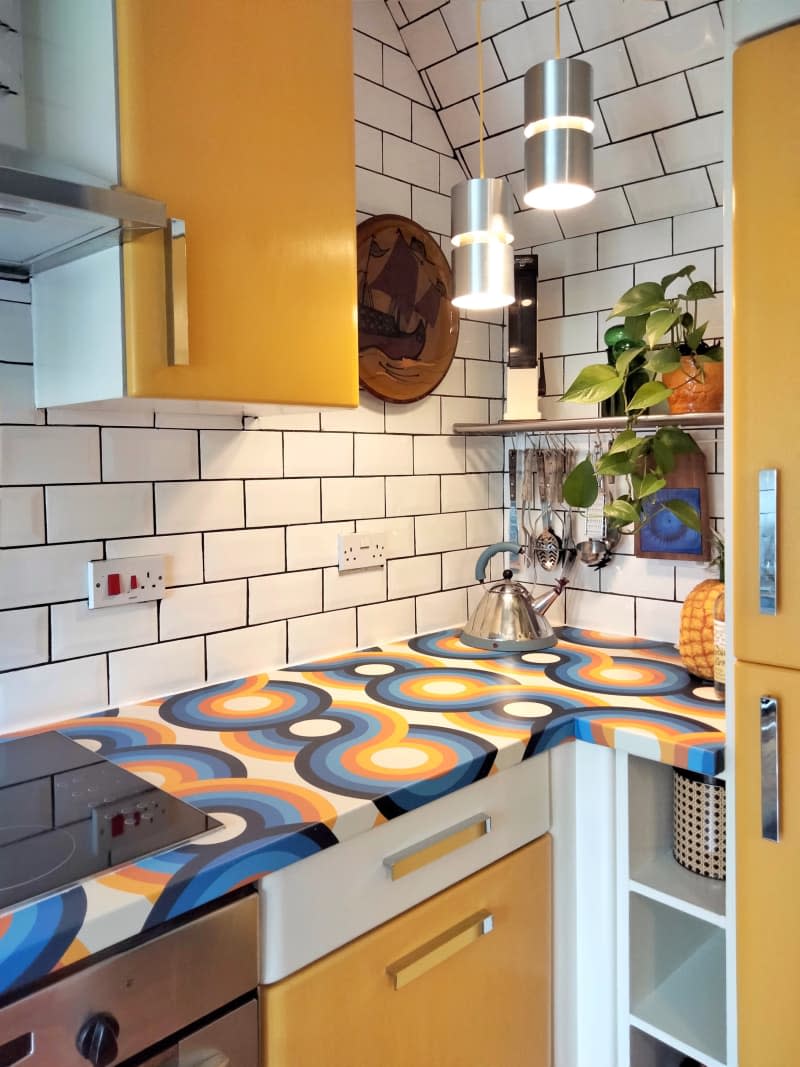 White tile backsplash, yellow cabinets and graphic countertop.