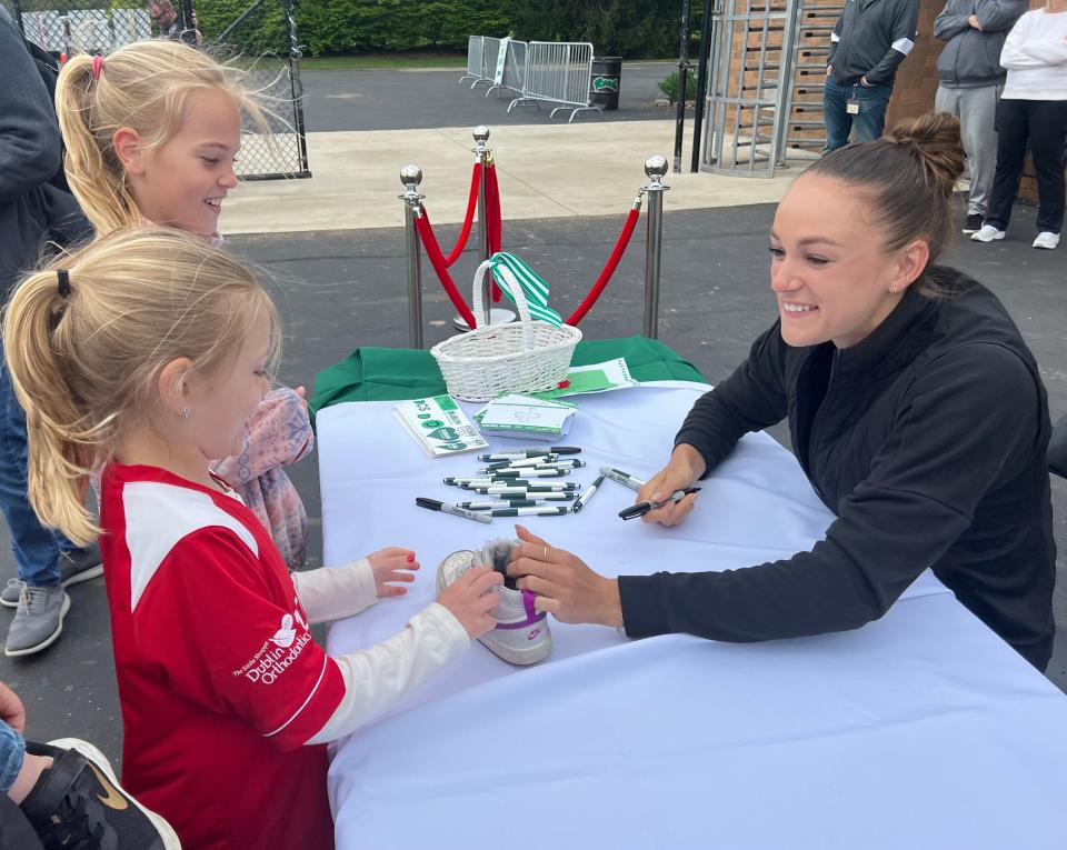 Dublin Coffman graduate Abby Steiner meets with sisters Annie Anania, front, and Natalie Anania during an unveiling of a mural in Steiner's honor Saturday at the school.