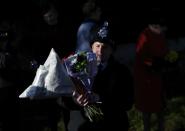 A police officer carries flowers offered to Britain's Queen Elizabeth as she leaves a Christmas Day morning service at the church on the Sandringham Estate in Norfolk, eastern England, December 25, 2013. REUTERS/Andrew Winning (BRITAIN - Tags: ROYALS RELIGION)