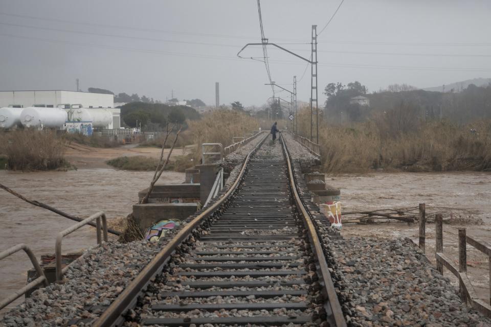 A man walks on a collapsed train track and a bridge due a heavy storm in Malgrat, near Barcelona, Spain, Wednesday, Jan. 22, 2020. Since Sunday the storm has hit mostly eastern areas of Spain with hail, heavy snow and high winds, while huge waves smashed into towns on the Mediterranean coast and nearby islands of Mallorca and Menorca. (AP Photo/Joan Mateu)