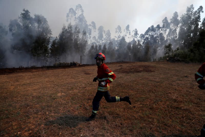 FILE PHOTO: A firefighter runs as he helps to put out a forest fire next to Fontao