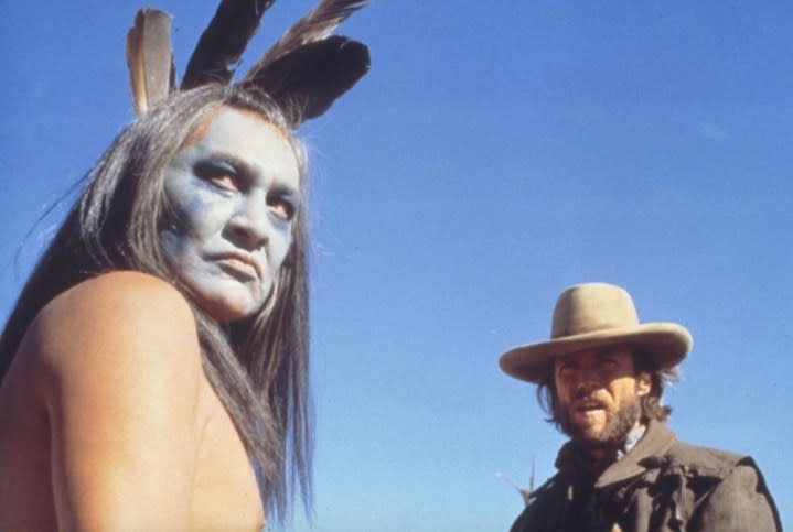 A Native American chief stands in front of an American outlaw.