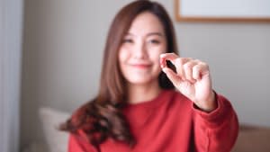 Closeup image of a young woman holding and looking at a red jelly gummy bears