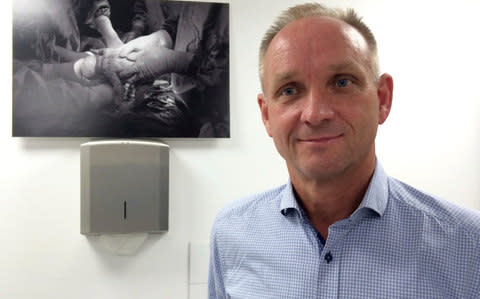 Mats Brannstrom poses besides a photo showing the birth of a baby of a mother with a womb transplant at Stockholm - Credit: Dorothy Thiesing/AP