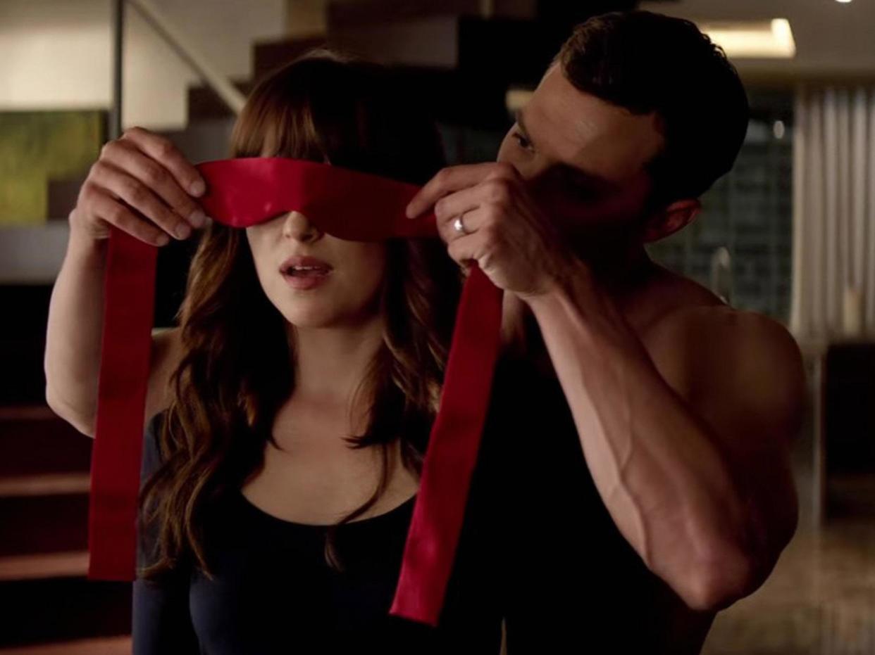 Christian Grey puts Ana Steele in a blindfold in Fifty Shades of Grey: Universal