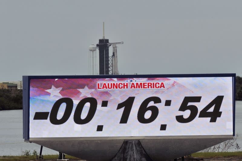 A screen showing the countdown clock is seen with SpaceX Falcon 9 rocket and Crew Dragon spacecraft in the background as launch from NASA's Kennedy Space Center was scrubbed, in Cape Canaveral