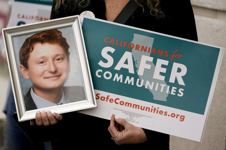 Juli Shamash holds up a photo of her son, Tyler Shamash, who passed away from a fentanyl overdose in 2018, during a news conference organized by the Californians for Safer Communities Coalition, Thursday, April 18, 2024, in Culver City, Calif. The coalition, backed by retailers like Walmart and Target, announced Thursday it has collected enough signatures to put a ballot measure before California voters this November to enhance criminal penalties for shoplifting and drug dealing. (AP Photo/Ryan Sun)