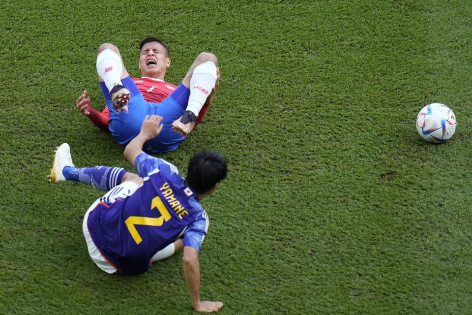 Costa Rica's Anthony Contreras, top, reacts after colliding with Japan's Miki Yamane during the World Cup, group E football match between Japan and Costa Rica, at the Ahmad Bin Ali Stadium in Al Rayyan, Qatar, Sunday, Nov. 27, 2022. (AP Photo/Hassan Ammar)