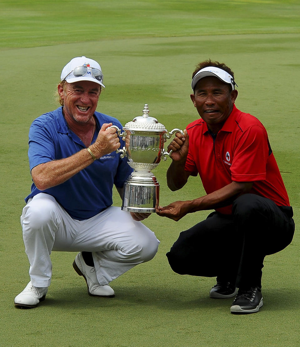 Miguel Angel Jimenez, left, of Spain and Thailand's Thongchai Jaidee, right, poses for the camera with the Eurasia trophy after both Team Asia and Euro drew during the third round of the Eurasia Cup golf tournament at the Glenmarie Golf and Country Club in Subang, Malaysia, Saturday, March 29, 2014.