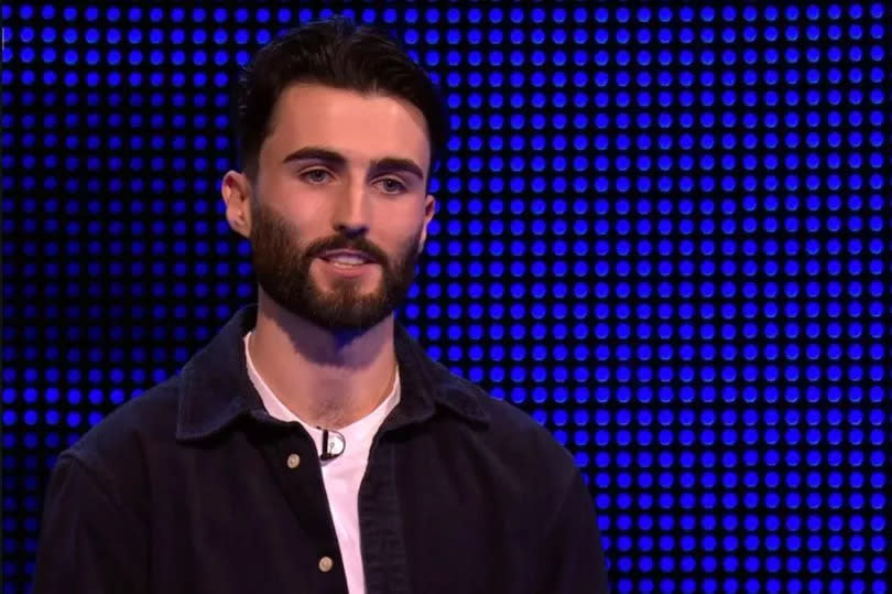 Theo on The Chase. He has a beard and is wearing a shite T shirt with a cargo jacket over the top.