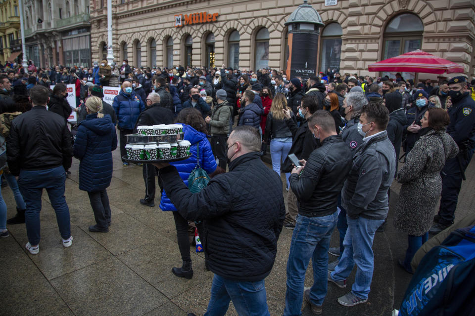 A protestor carries a tray of coffee cups as several thousand owners of restaurants, bars and other businesses that have been shut down during the coronavirus pandemic rally against government measures in Zagreb, Croatia, Wednesday, Feb. 3, 2021. The protests was organized by an association of entrepreneurs who are demanding that they be allowed to work while respecting the coronavirus safety rules. (AP Photo/Darko Bandic)