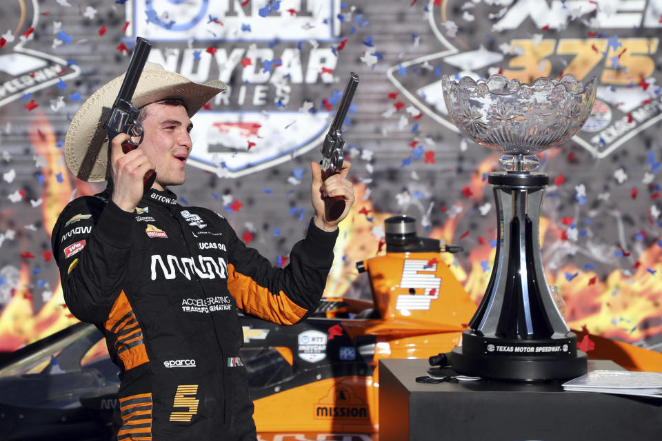 Pato O'Ward holds a pair of pistols as he celebrates his victory at an IndyCar Series auto race at Texas Motor Speedway on Sunday, May 2, 2021, in Fort Worth, Texas. (AP Photo/Richard W. Rodriguez)