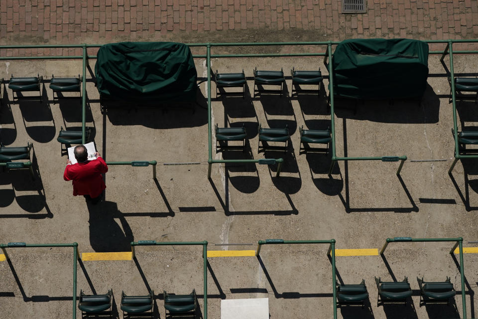 A man looks over a racing program before the 147th running of the Kentucky Derby at Churchill Downs, Saturday, May 1, 2021, in Louisville, Ky. (AP Photo/Charlie Riedel)