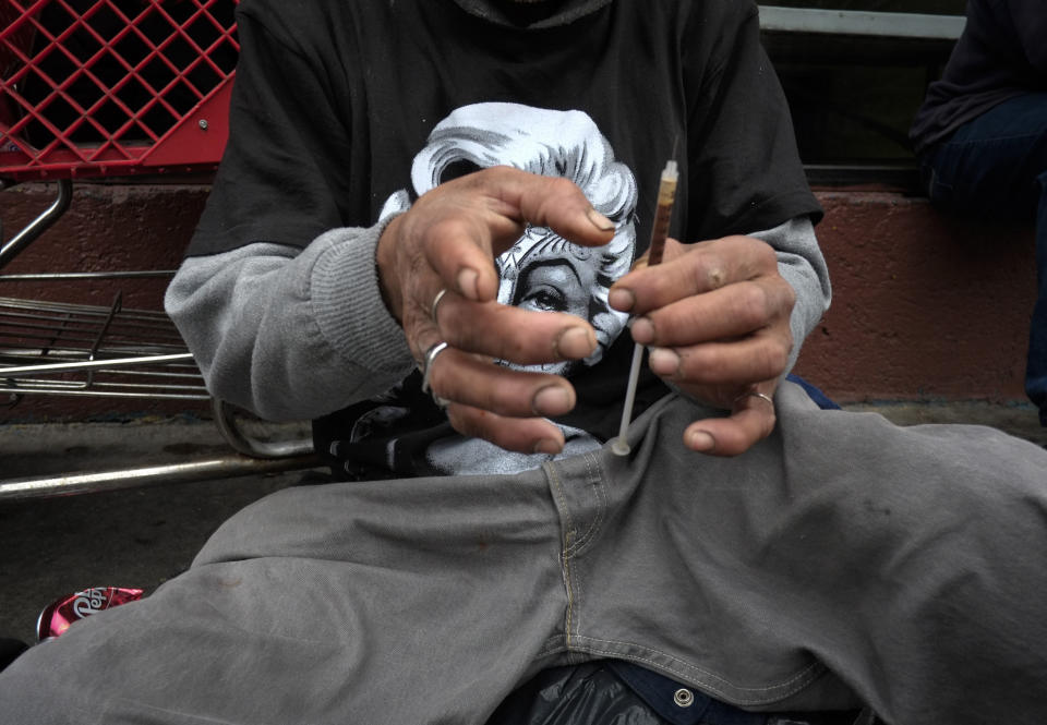 FILE - In this Monday, May 6, 2013 file photo, a drug addict prepares a needle to inject himself with heroin in front of a church in the Skid Row area of Los Angeles. The death of actor Philip Seymour Hoffman in February 2014 spotlighted the reality that heroin is no longer limited to the back alleys of American life. Once mainly a city phenomenon, the drug has spread to the country and suburbs. (AP Photo/Jae C. Hong)