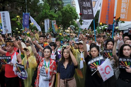 Same-sex marriage supporters hold roses to mourn those who committed suicide due to discrimination during a parliament vote on three draft bills of a same-sex marriage law, outside the Legislative Yuan in Taipei, Taiwan May 17, 2019. REUTERS/Tyrone Siu