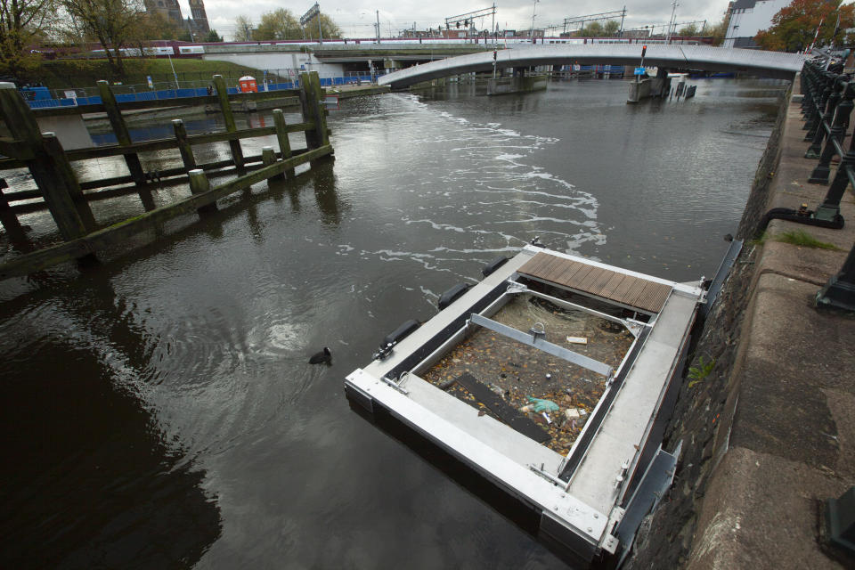 FILE - A device that uses a curtain of tiny air bubbles to catch floating plastic and move it to a collector, bottom right, in the capital's canals works on Nov. 6, 2019, in Amsterdam, Netherlands. The Great Bubble Barrier captures plastic floating on and in the water while letting wildlife and boats pass by. (AP Photo/Peter Dejong)