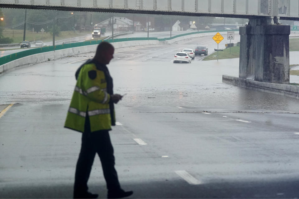 Flood waters cover a closed highway as a law enforcement officer stands by in Dallas, Monday, Aug. 22, 2022. (AP Photo/LM Otero)
