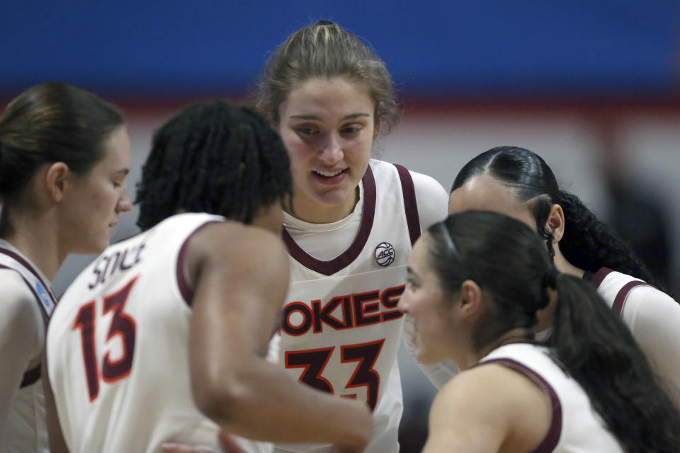 Virginia Tech's Elizabeth Kitley (33) huddles with teammates during second-round college basketball game in the women's NCAA Tournament, Sunday, March 19, 2023, in Blacksburg, Va. Even the handful of players selected in the upcoming WNBA draft will find it difficult to continue their pro careers. Kitley is thinking twice about leaving college, where they enjoy various amenities due to Title IX, including taking charter flights vs flying commercial.(AP Photo/Matt Gentry)