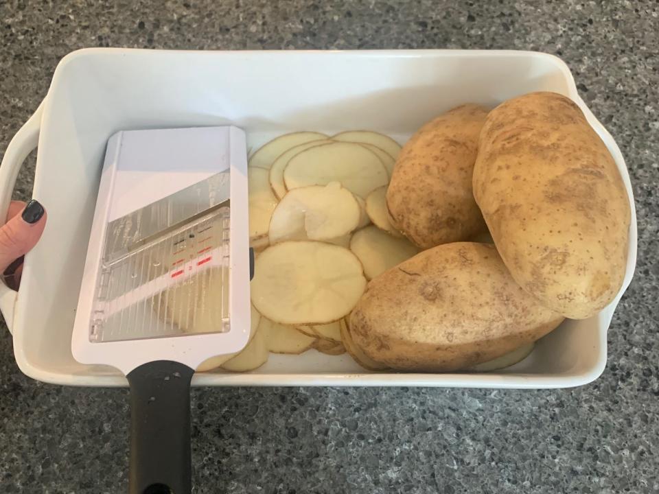 potatoes and thin potato slices in a container with a mandolin