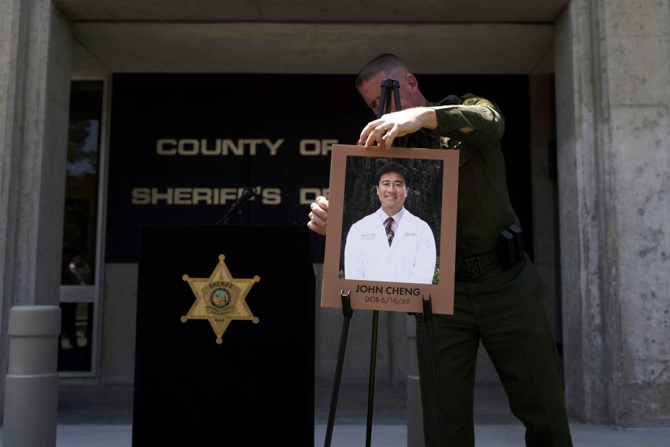 FILE - Orange County Sheriff's Sgt. Scott Steinle displays a photo of Dr. John Cheng, a 52-year-old victim who was killed in Sunday's shooting at Geneva Presbyterian Church, before a news conference in Santa Ana, Calif., Monday, May 16, 2022. After a weekend of gun violence in America, when shootings killed and wounded people grocery shopping, going to church and simply living their lives, the nation marked a milestone of 1 million deaths from COVID-19. The number, once unthinkable, is now a pedestrian reality in the United States, just as is the reality of the continuing epidemic of gun violence that kills tens of thousands of people a year. (AP Photo/Jae C. Hong, File)