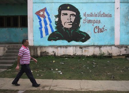 A man walks past near an image of revolutionary hero Ernesto "Che" Guevara in Havana December 27, 2014. REUTERS/Stringer