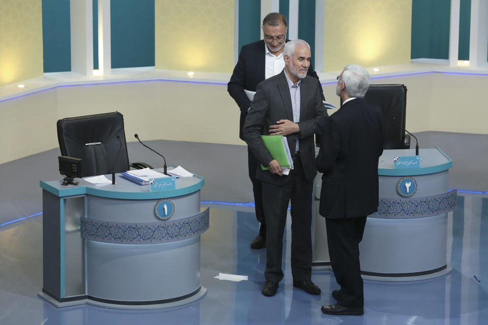 In this picture made available by Young Journalists Club, YJC, presidential candidates for June 18, elections Mohsen Mehralizadeh, center, Alireza Zakani, top, and Saeed Jalili, talk at the conclusion of a part of the final debate of the candidates at a state-run TV studio in Tehran, Iran, Saturday, June 12, 2021. Iran's seven presidential candidates offered starkly different views Saturday in the country's final debate, with hard-liners describing those seeking ties with the West as "infiltrators" and the race's sole moderate warning a hard-line government would only bring more sanctions for the Islamic Republic. (Morteza Fakhri Nezhad/ Young Journalists Club, YJC via AP)