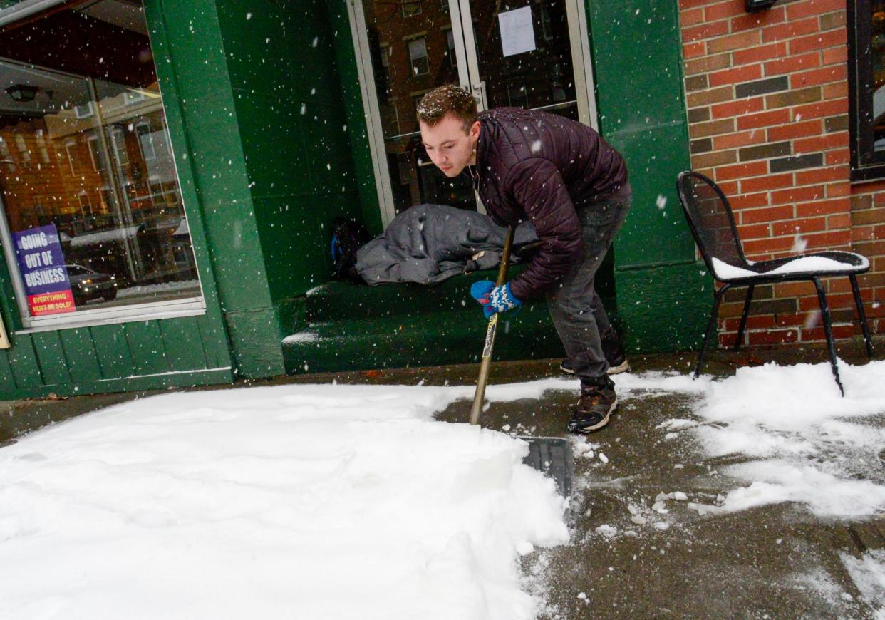 <span>A restaurant worker shovels a sidewalk in Brattleboro, Vermont, as a person who is facing homelessness sleeps in a doorway during a snowstorm on 23 March 2024. </span><span>Photograph: Kristopher Radder/AP</span>