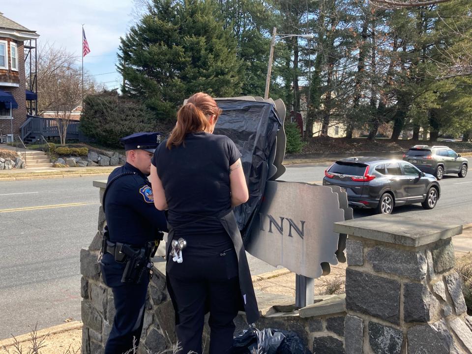 A Wilmington police officer and Columbus Inn employee cover up a graffitied Nazi symbol on Feb. 12, 2022.